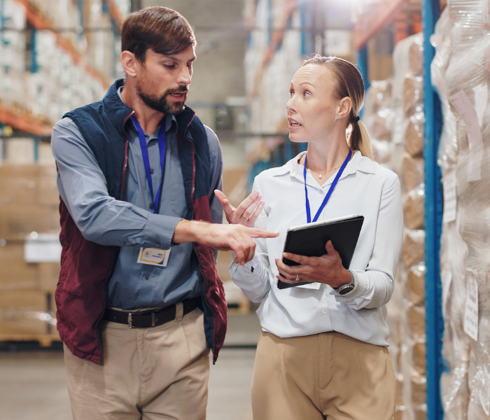 Visio Logistiikka, kaksi työntekijää kävelemässä varastossa.